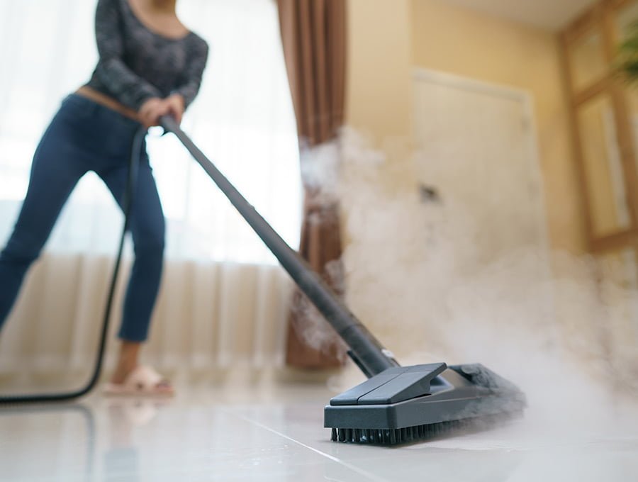 Esta mujer limpia el suelo del salón con un limpiador a vapor.